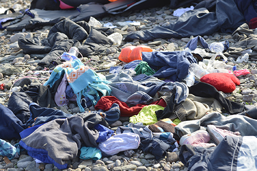 Des vêtements usagés sont échoués sur une plage de galets