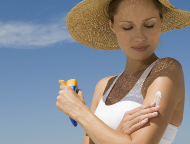 Une femme applique de la crème solaire biodégradable sur sa peau.