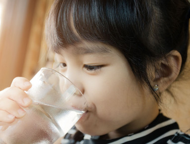 Une petite fille boit un verre d’eau.