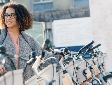 Une femme prend un vélo en libre-service sur une station.