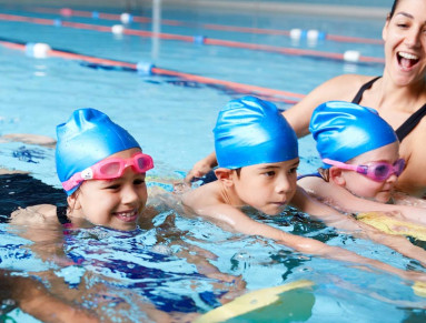 Quatre enfants suivent un cours de natation avec leur professeur.
