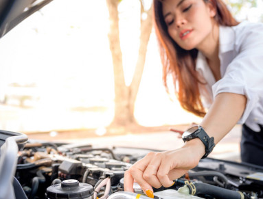 Une femme vérifie le niveau d’huile moteur de sa voiture.