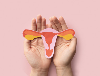 Une femme tient entre ses mains le dessin d’un utérus.