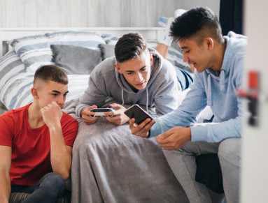 Trois adolescents jouent à des jeux d'argent sur leur téléphone.