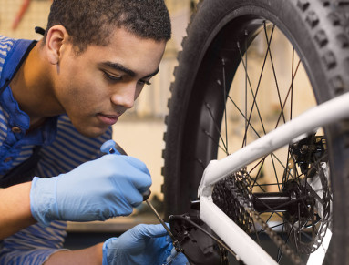 Un jeune mécanicien répare une roue de vélo