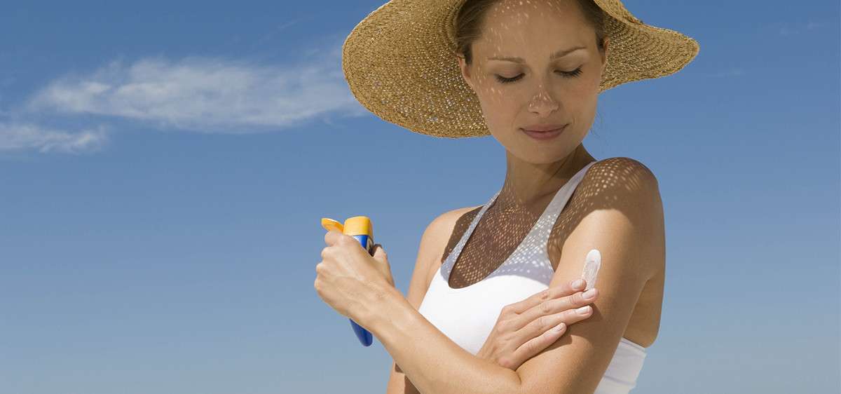 Une femme applique de la crème solaire biodégradable sur sa peau.