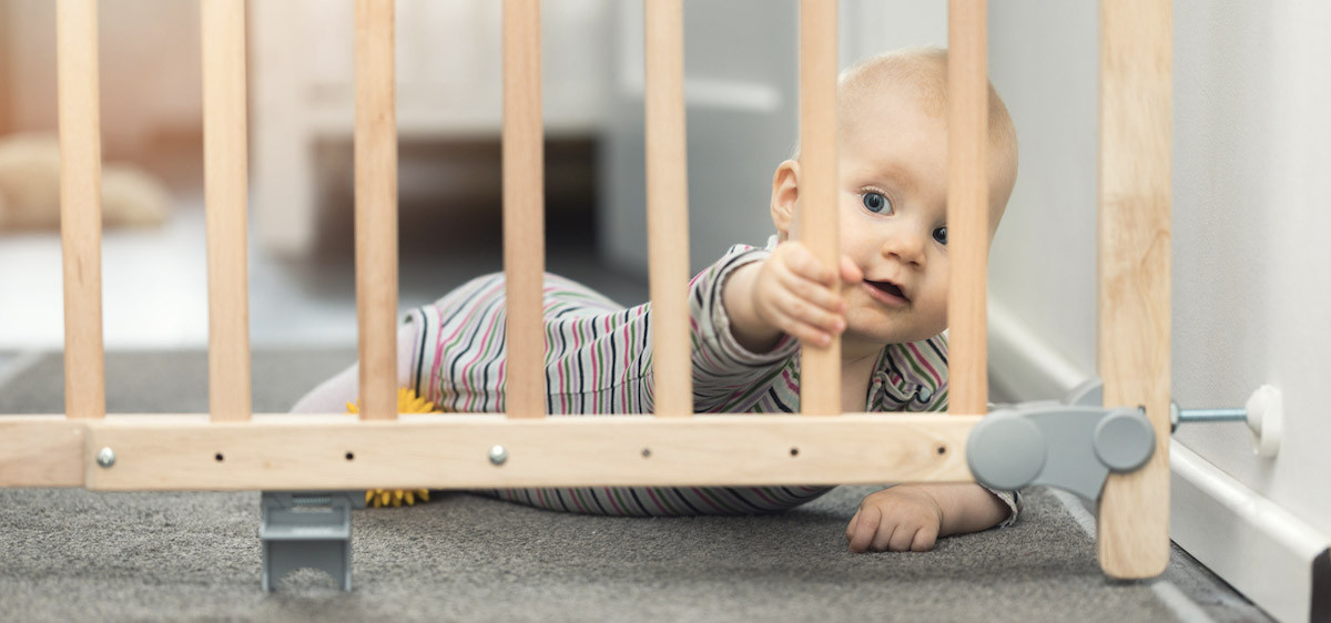 Un enfant en bas âge s’approche des marches de l’escalier, protégé par une barrière.