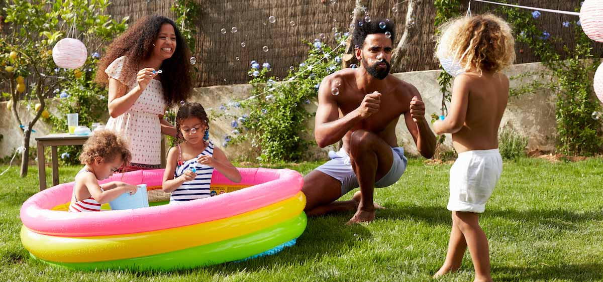 Des parents jouent avec leurs enfants dans une petite piscine gonflable.