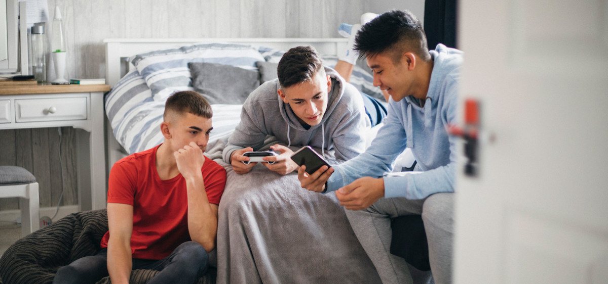 Trois adolescents jouent à des jeux d'argent sur leur téléphone.