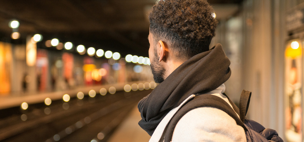 Un jeune homme de profil attend le RER un quai